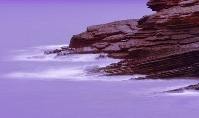 minimalist abstract landscape of rocks entering a purple sea - 512293487