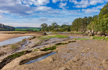estuary landscape with low tide and blue sky with clouds - 512293488