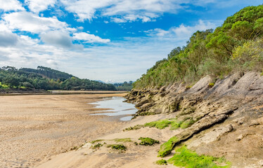 estuary landscape with low tide and blue sky with clouds - 512293492