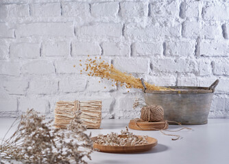 Cotton flower and wicker bag vase of plant style on the white table, brick wall background, still life, decoration.