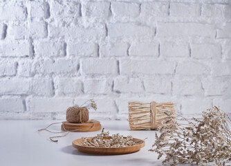 Fototapeta na wymiar Cotton flower and wicker bag vase of plant style on the white table, brick wall background, still life, decoration.
