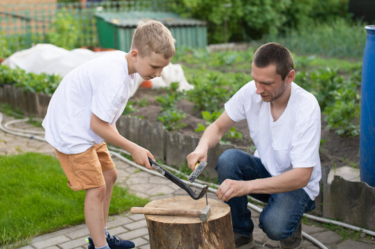 Dad teaches his son to hammer nails into a tree