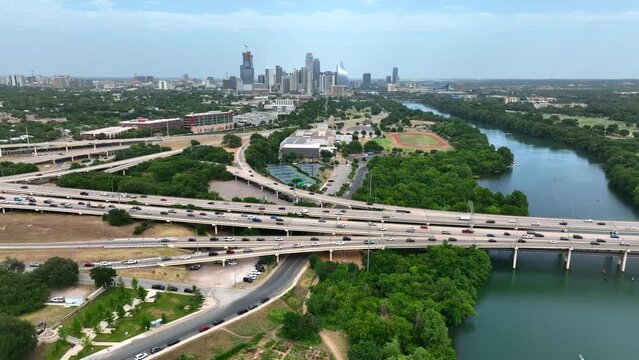 Wide aerial reveals interstate highway freeway traffic with Austin Texas skyline in distance. Commuter traffic in quickly growing city in USA.