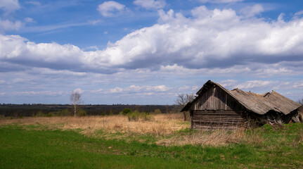 an old abandoned village barn with a collapsed roof sky and clouds