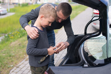 Fototapeta na wymiar Dad teaches his cute son to use a car repair tool