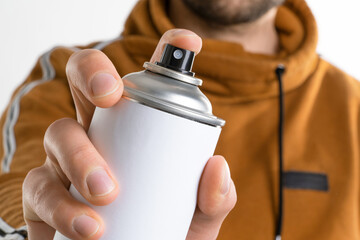 Man's hand holds a can of aerozols