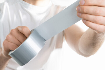 Close up image of mand holding adhesive tape on white background trying to fix something