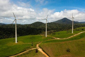 Fototapeta na wymiar Group of wind turbines among green pastures and hills. Wind power plant. Ambewela, Sri Lanka.