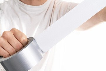 Close up image of mand holding adhesive tape on white background trying to fix something