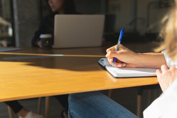 Crop businesswoman taking notes during meeting