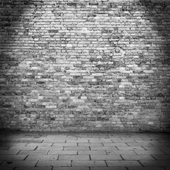 brick wall texture background in basement and beam of lamp lightand sidewalk urban background or grunge scene