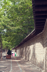 서울에 있는 덕수궁의 돌담길을 걷고 있는 한복을 입은 사람.