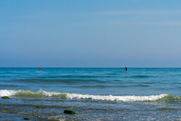 Fototapeta na wymiar Two paddle board surfers on the calm waters of the Mediterranean Sea