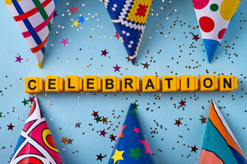 Obraz premium Flat lay celebration word and birthday cones with confetti. Isolated on blue background.