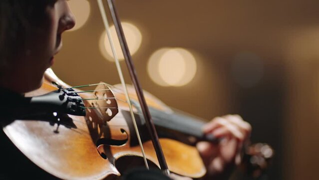 closeup view of violin in hands of female player, woman violinist in opera house, classic music concert