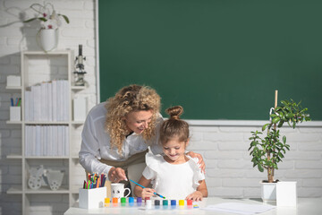 Back to school. Kid drawing with teacher. Children from elementary school study at draw lesson. Pupil with teacher painting.