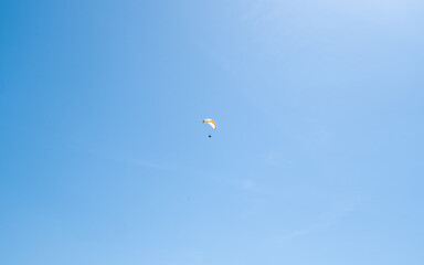 Naklejka na ściany i meble Mountain paragliding in the blue sky. Extreme sport concept