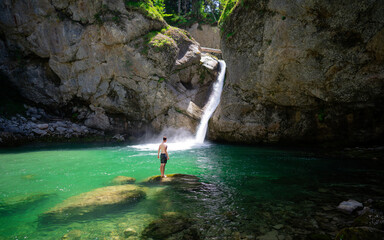 Traveler adventure standing on the rock and happy with the waterfall.  Blue crysral water in the...