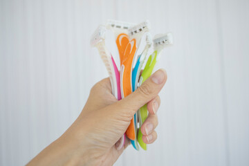 a razor to remove excess hair in the hand of a young fair-skinned girl, on a light background....
