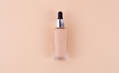 Liquid foundation cream unbranded bottle on a beige background. BB cream for professional make-up, eyedropper for applying to the face. Cosmetic female accessory, fluid. Mock up concept