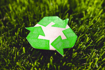 recycle sign hand drawn on cardboard resting on perfect green grass from private lawn