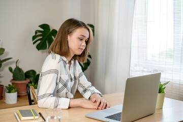 Beautiful young woman entrepreneur working on laptop at home. Female freelancer working at home office. Girl using a computer for study online at home. Remote work or study concept.