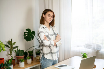 Young woman entrepreneur working at home. Girl using a computer for study online at home office, female user busy on a distance internet job. Cozy office workplace, remote work, e-learning concept. 