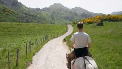 Hombre a caballo subiendo una cuesta en ruta de montaña desde atrás