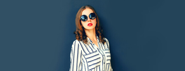 Portrait of beautiful young woman wearing white striped shirt on dark background