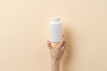 Femal hand holds a bottle of medication pills
