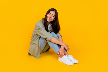 Full body portrait of adorable cheerful friendly person sit floor beaming smile isolated on yellow color background
