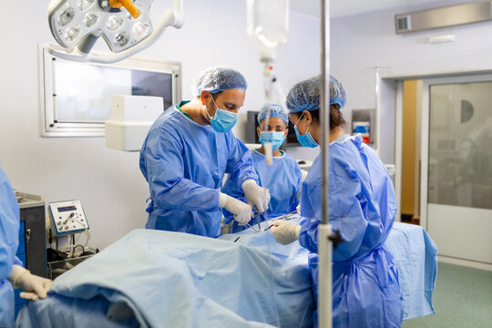 Group of medical team urgently doing surgical operation and helping patient in theater at hospital. Medical team performing surgical operation in a bright modern operating room