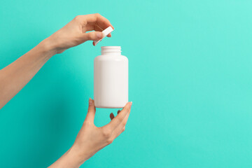 Female hand holding white bottle of medication pills  or vitamins or supplements