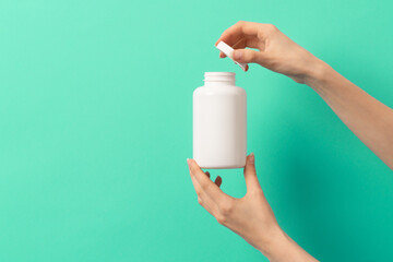 Female hand holding white bottle of medication pills  or vitamins or supplements