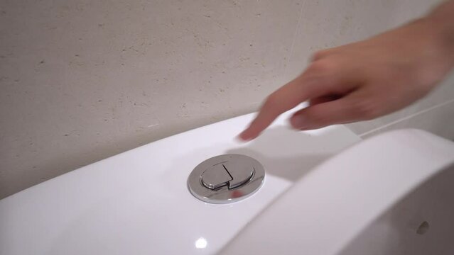 Young woman presses button in toilet with her finger. Macro photography. hands men, press water button, flush toilet, concept of health. economical drain. Water saving