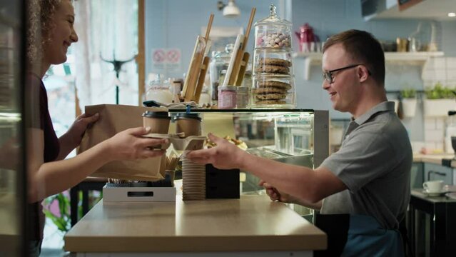 Caucasian man with down syndrome giving take away food to a female client. Shot with RED helium camera in 8K. 