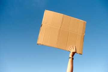 A cardboard Signs empty held by a hand on sky background