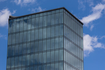 Plakat Modern office building with glass facade on a clear sky background. Transparent glass wall of office building.
