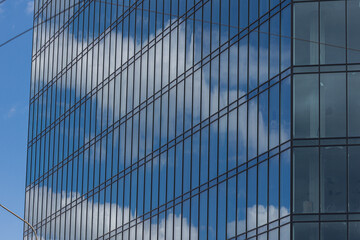Fototapeta na wymiar Modern office building with glass facade on a clear sky background. Transparent glass wall of office building.