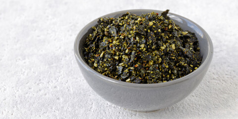 Vegan furikake seasoning with torn nori seaweed. Japanese cuisine condiment in bowl.