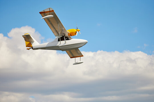 Closeup image of amphibian one-engine airplane at blue sky with clouds background. Aircraft wallpaper. Concept of tourism.