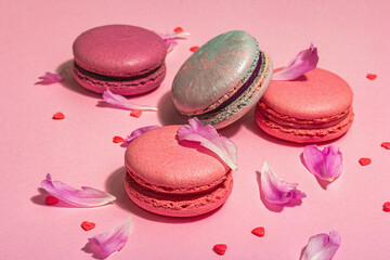 Obraz na płótnie Canvas Macarons with peonies flower petals on pink background. Sweet dessert, colorful and pastel candies