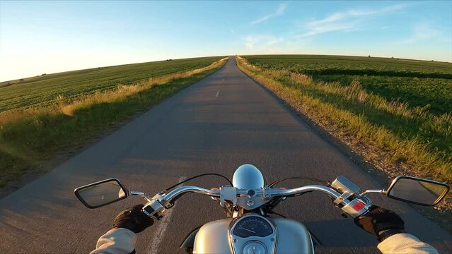 Biker driving a motorcycle rides along the asphalt road. First person view