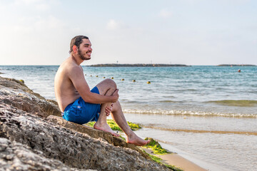 Man sitting on rock enjoying sea view, travel vacations eco tourism outdoor.