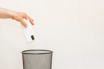 The smartphone is thrown into the trash for disposal and recycling.White,gray background,selective...