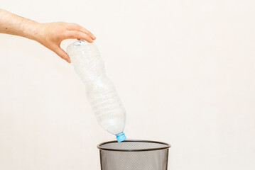 The plastic bottle is thrown into the trash basket for disposal and recycling.White,gray background,selective focus,copy space.