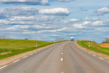 Fototapeta na wymiar Cars asphalt road through the green agricultural fields background on a sunny summer day.