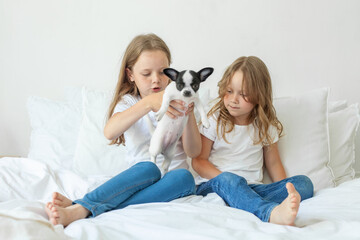 little sisters with puppy dog pet playing together at home