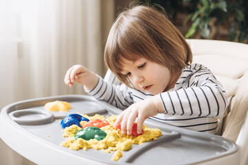 Cute little boy playing with kinetic sand. Development of fine motor skills. Early sensory education. Activities Montessori. Sensory plays at home.