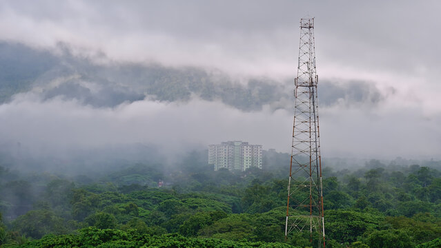 A MULTISTAGE BUILDING SURROUNDED BY CLOUD AND MOUNTAINS IN INDIA